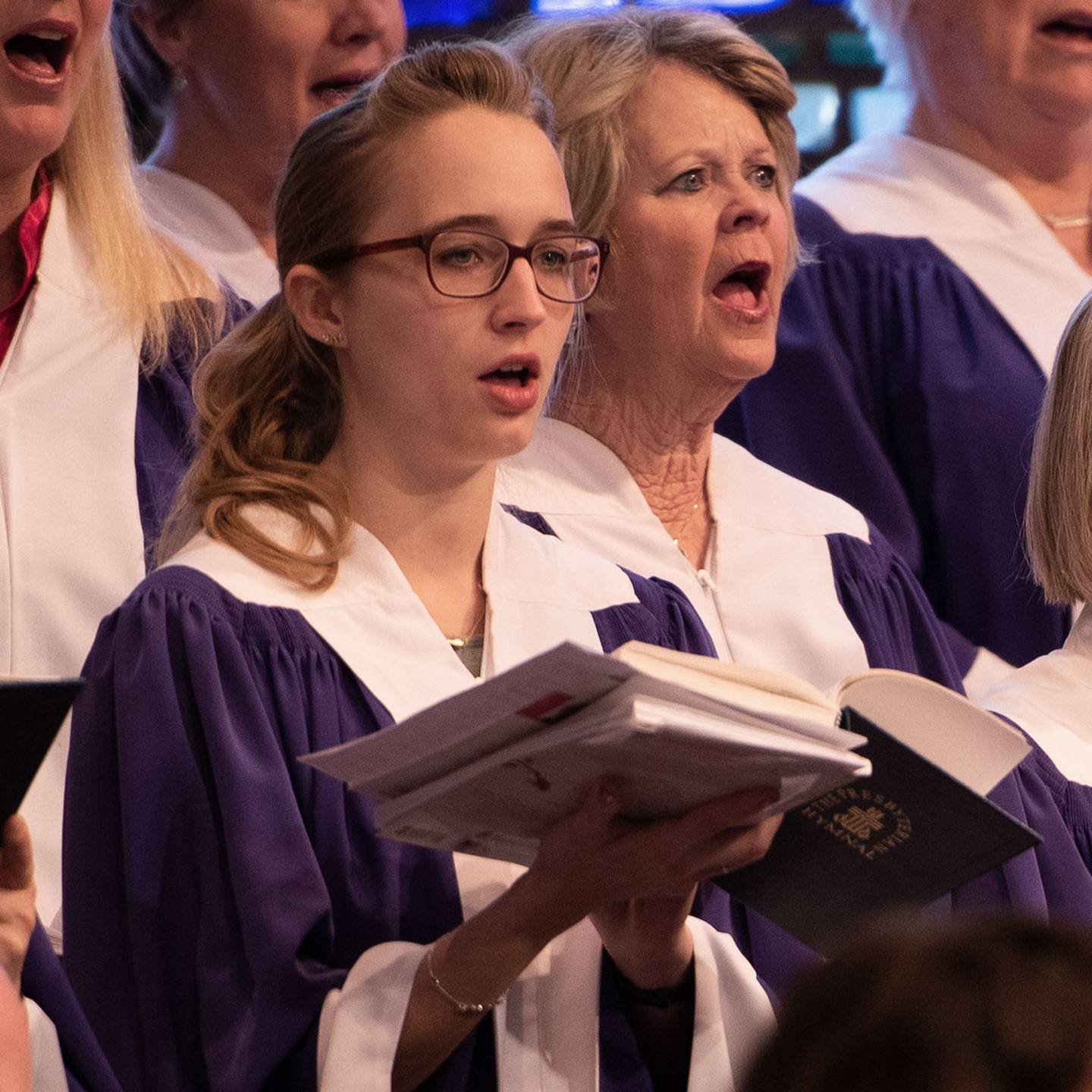 a close up of a woman in a choir singing