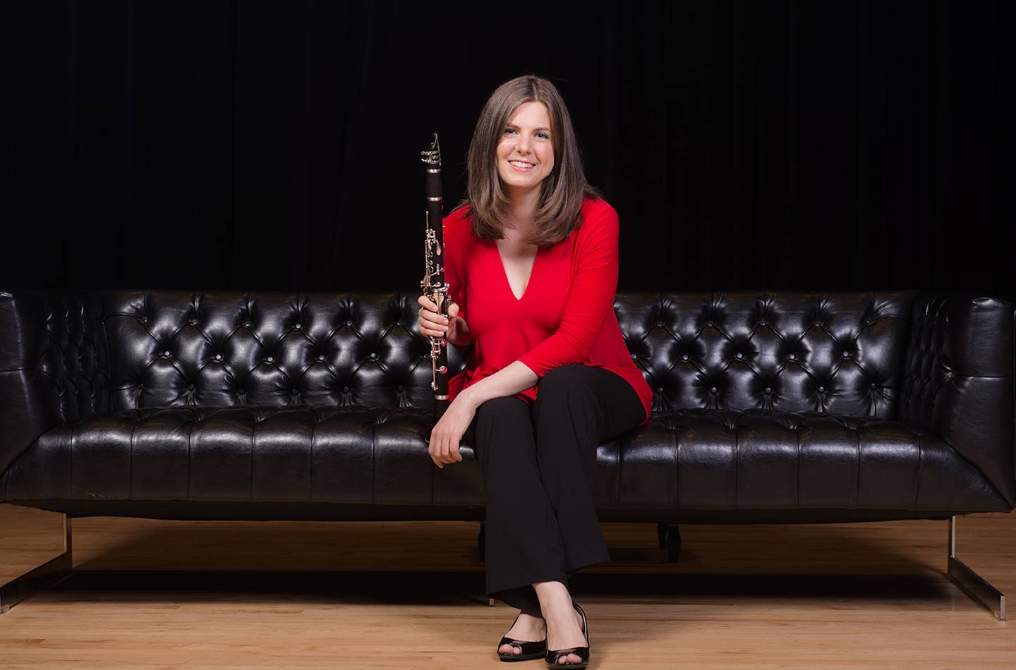 woman in red shirt sitting on couch holding instrument