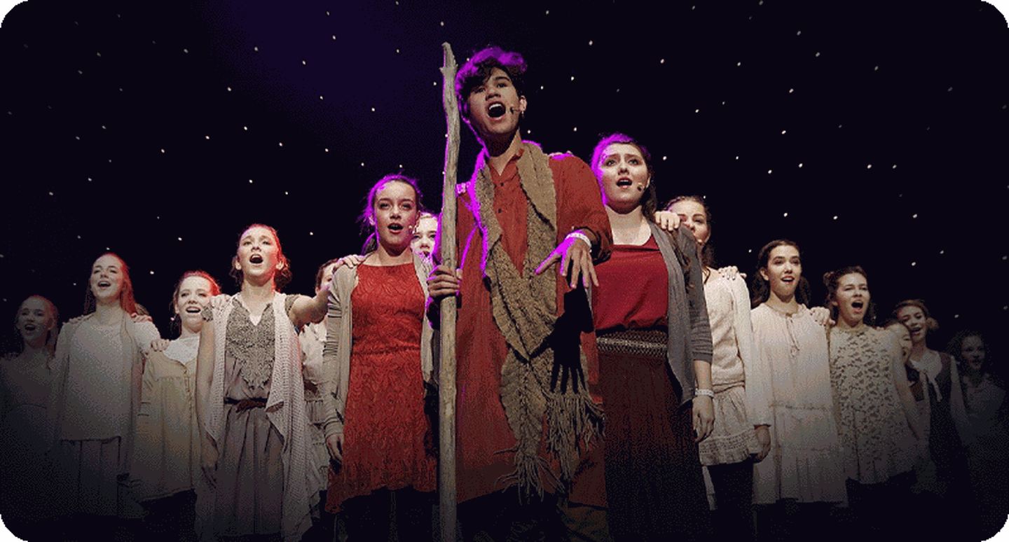 Teens on stage performing a Broadway Junior show.
