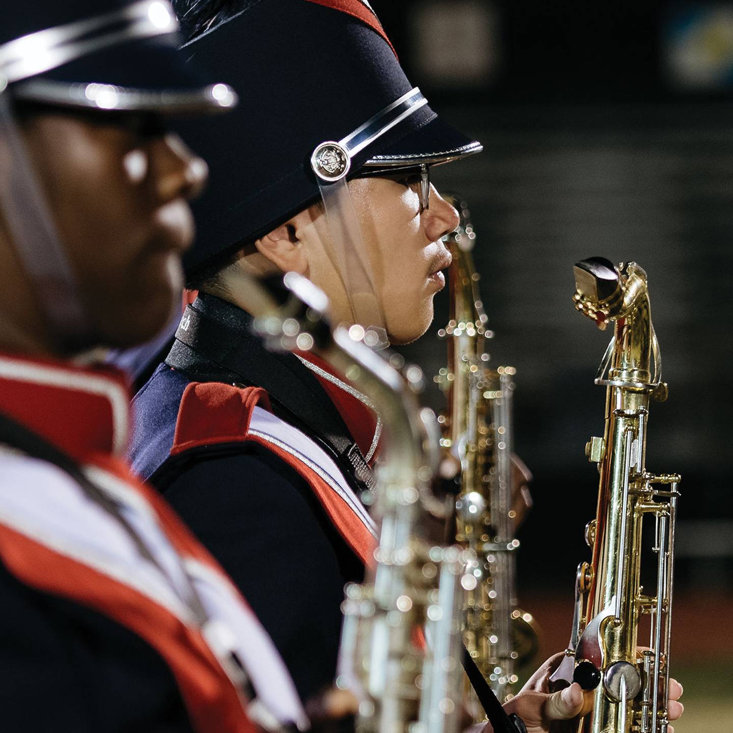 a close up of a man playing a saxaphone in a marching band