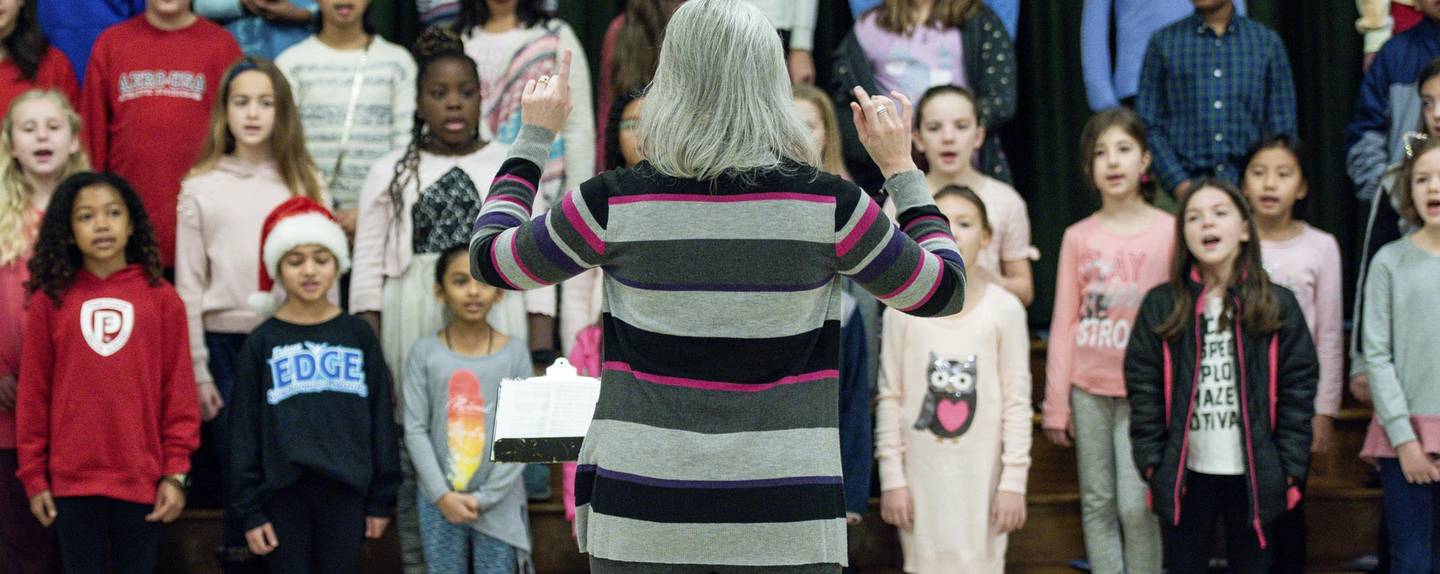 music director facing young choir singing