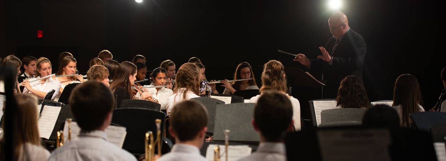 Director conducting school concert band performance.